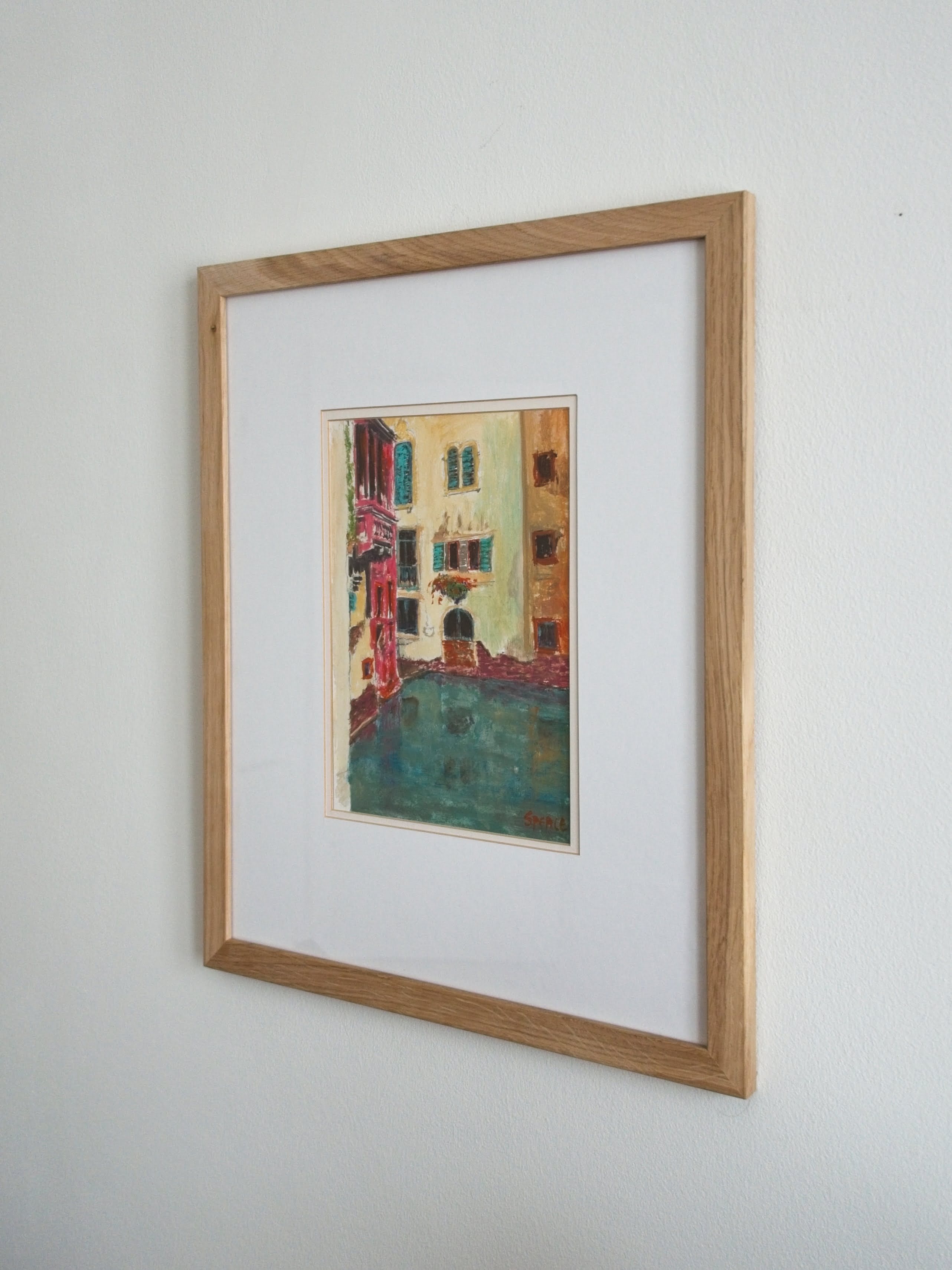 A brightly coloured 1980s original one of a kind vintage pine framed artwork of a Venice canal on a white wall.