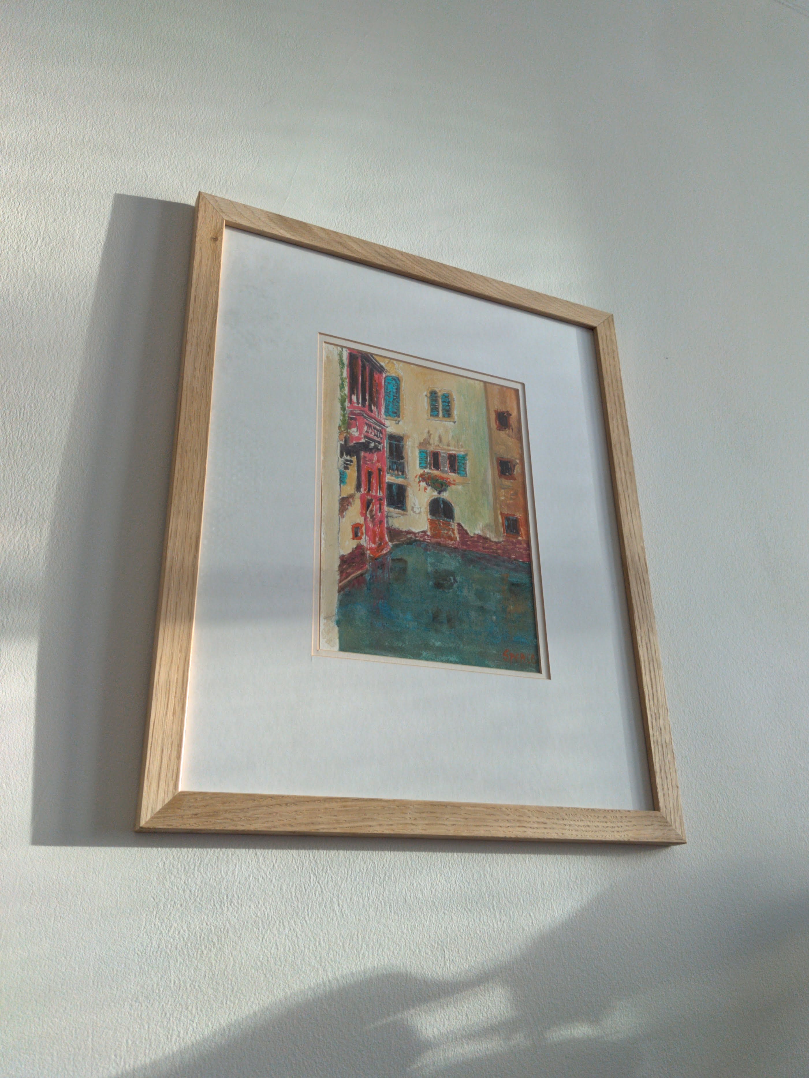 A wooden framed colourful mid century modern impressionist style vintage painting of the Venice canals on a white wall with leaf shaped shadows cast on the wall below.