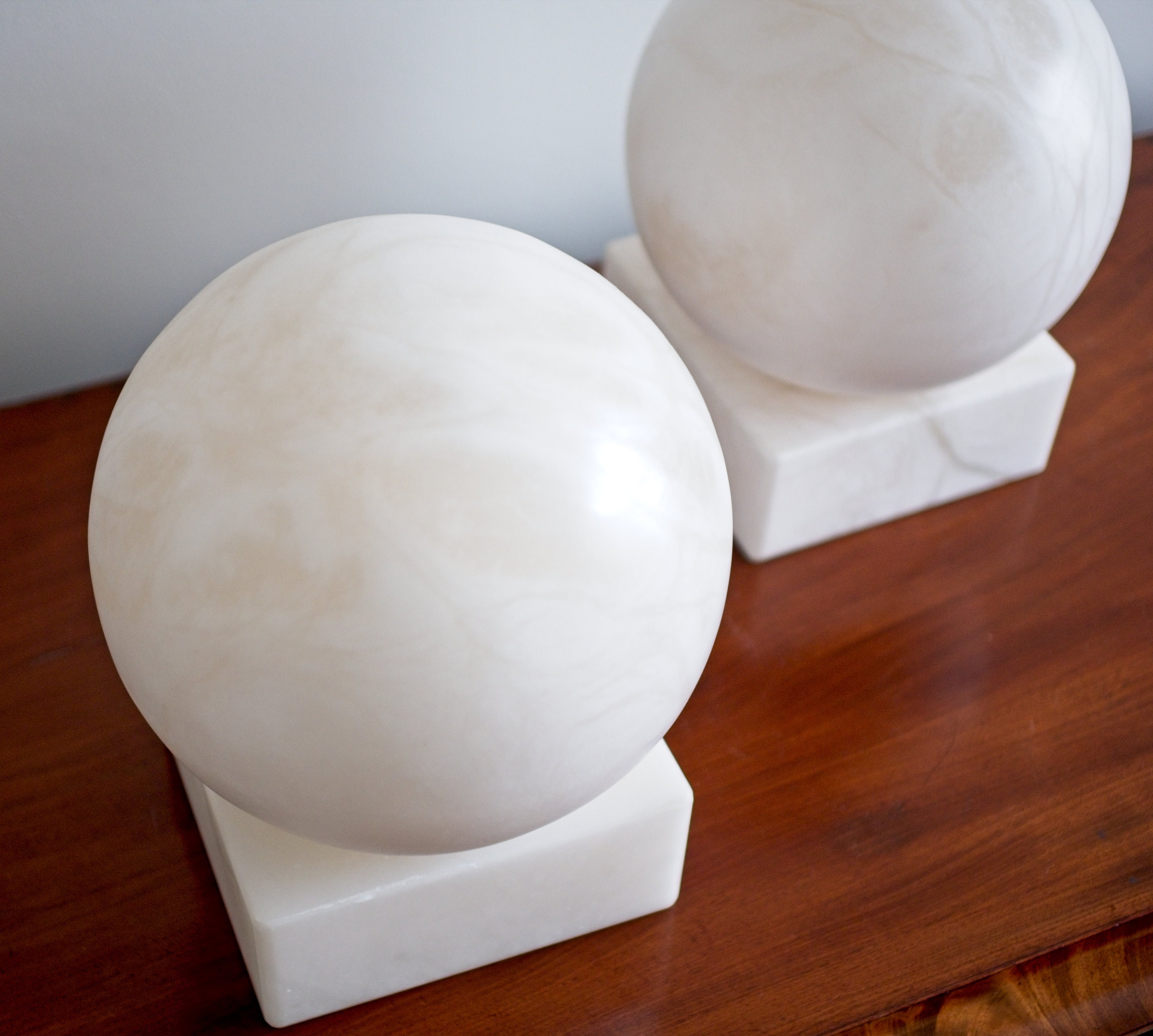 Two white marble spheres on a wooden surface with a neutral background.
