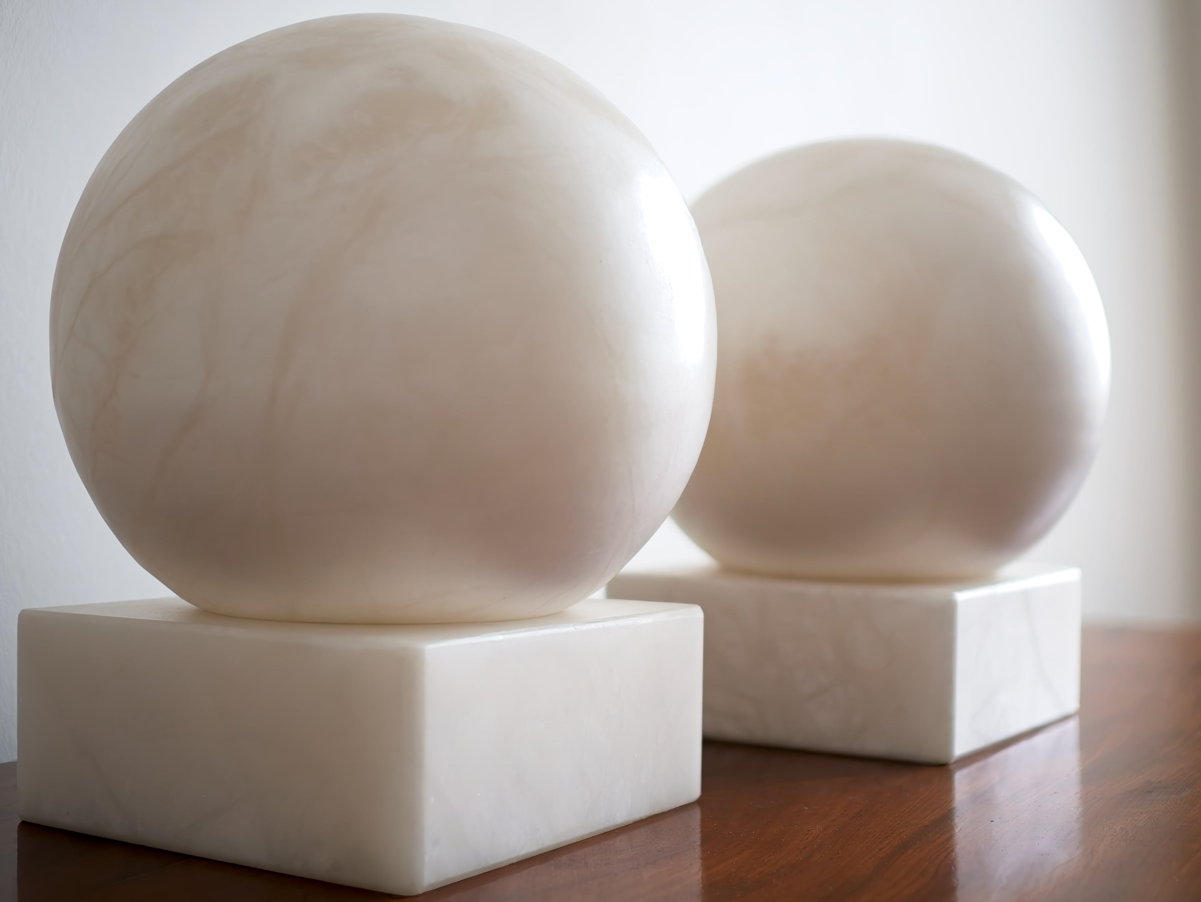 Two marble spheres on square bases against a white background