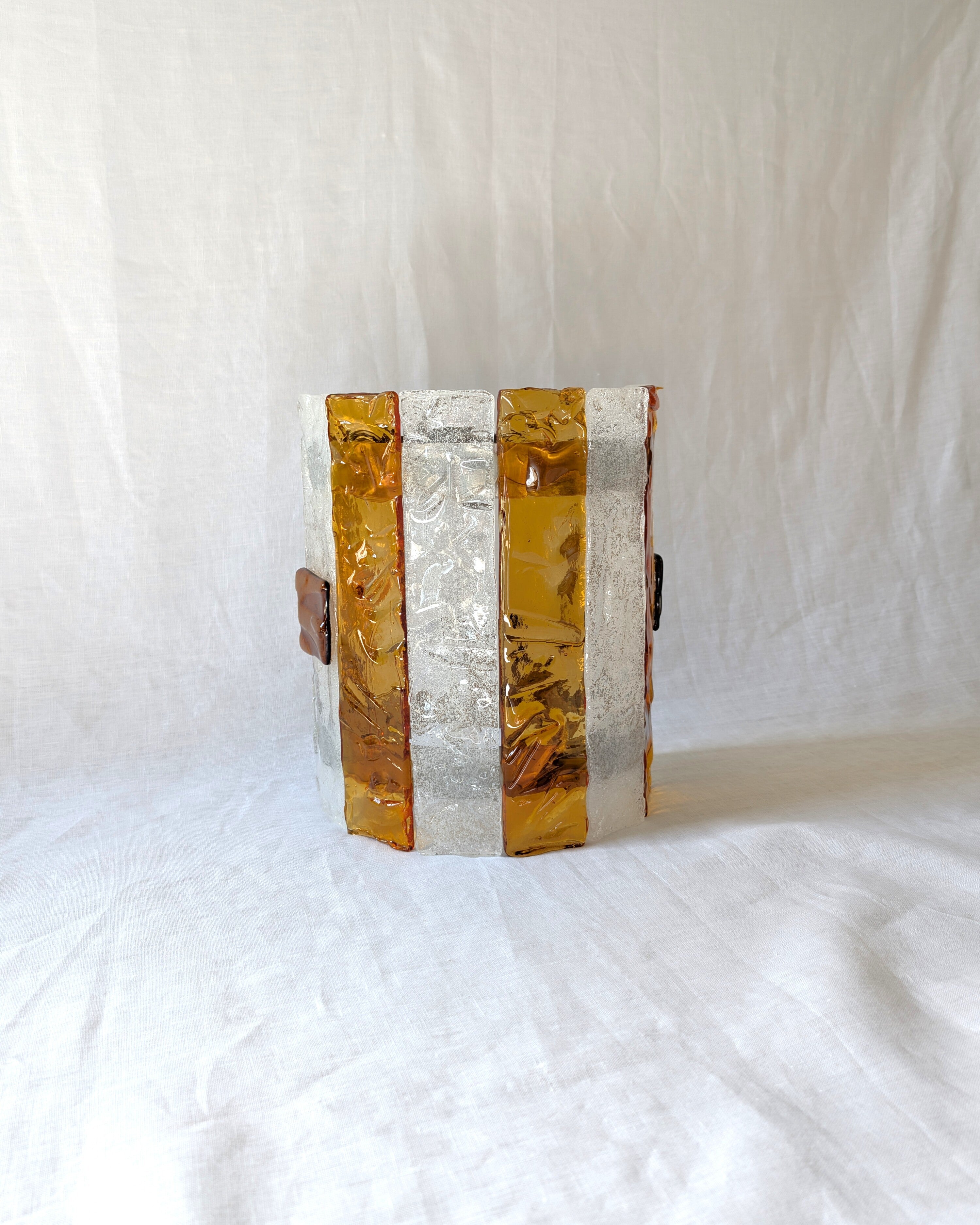 A vintage mid century modern 1970s Carlo Nason for Mazzega rectangular wall sconce with textured amber and clear striped Murano glass panels on white linen surface.