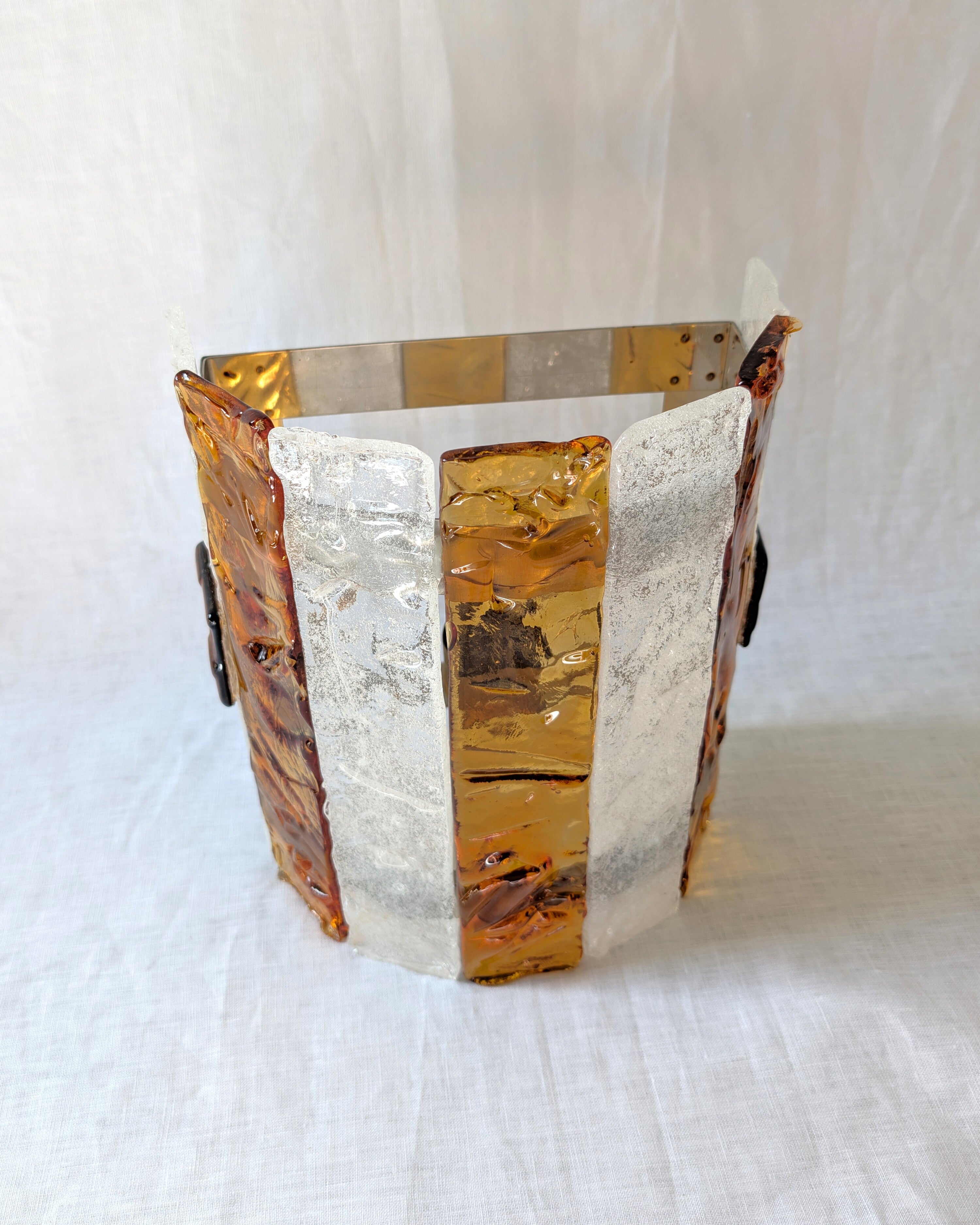 A vintage mid century modern 1970s Carlo Nason for Mazzega rectangular wall sconce with textured amber and clear striped Murano glass panels on white linen surface.