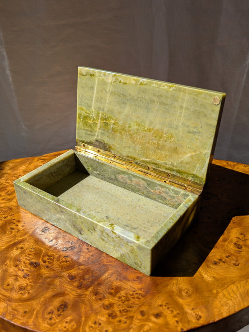 An antique green marble decor box by Henry Griffith & Sons, open to show the inside, on a Hollywood Regency style burl wood table. This rare Victorian decor box, made from hand carved solid Italian marble similar to onyx or jade, can be used as a trinket box, jewellery holder or cigar box and would be a beautiful addition to a vintage eclectic, mid century modern, minimalist, modernist, maximalist, baroque or art deco home interior schemes.