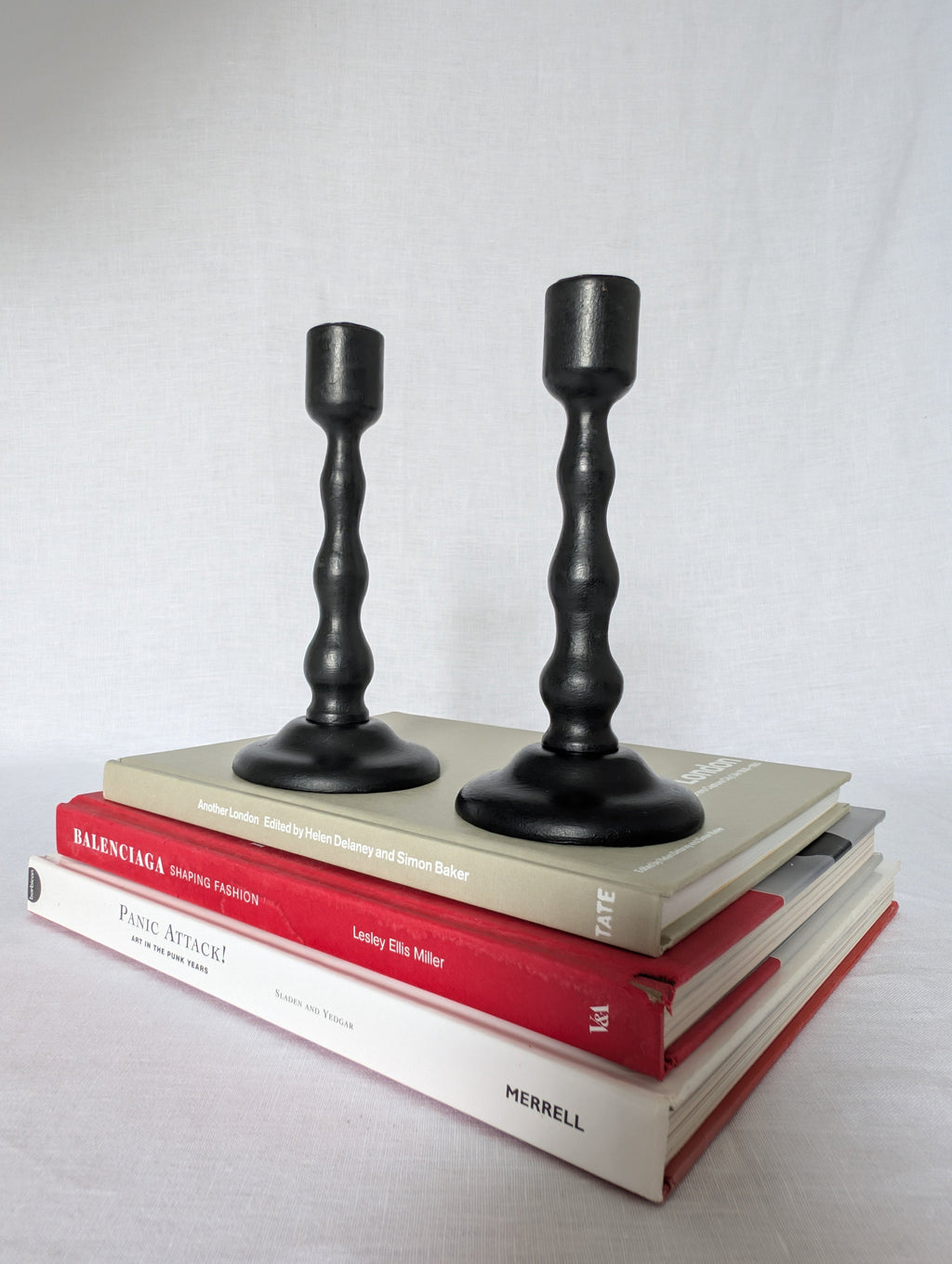 Two black candlesticks on top of books with a plain background