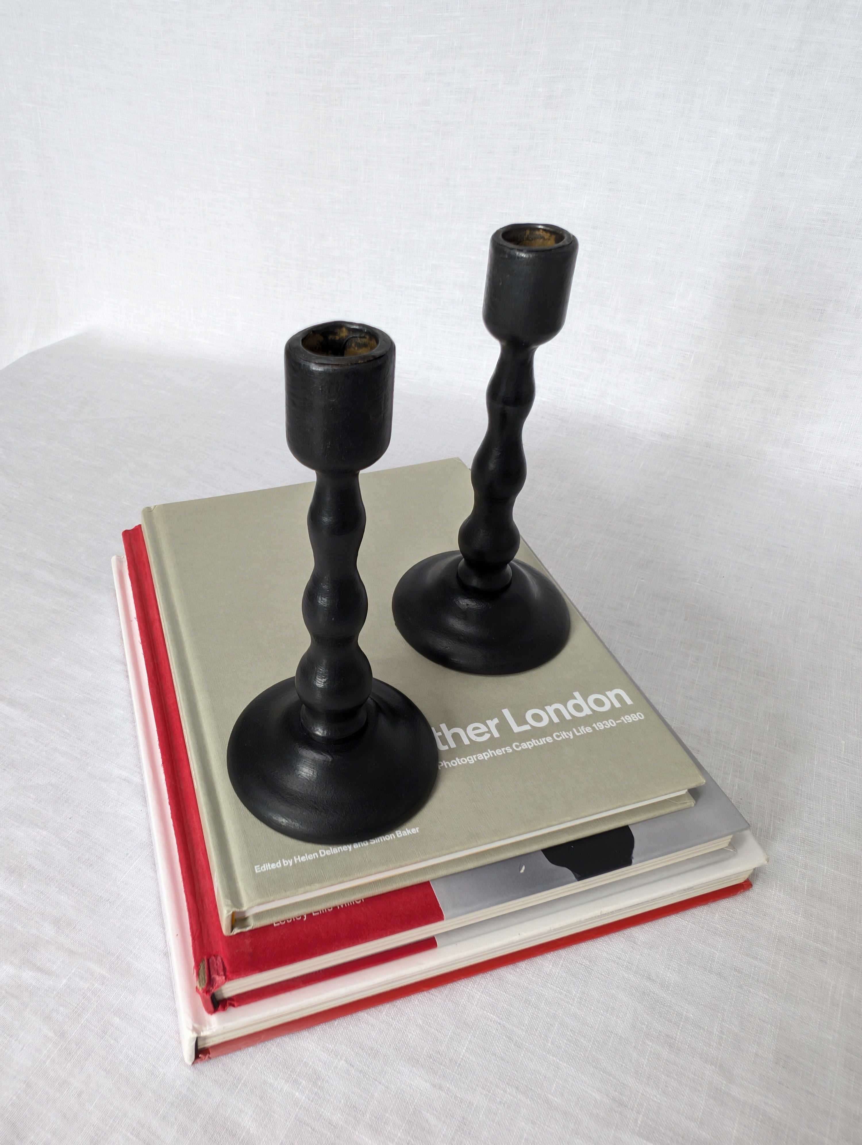 Two black candlesticks on a stack of books with a white background