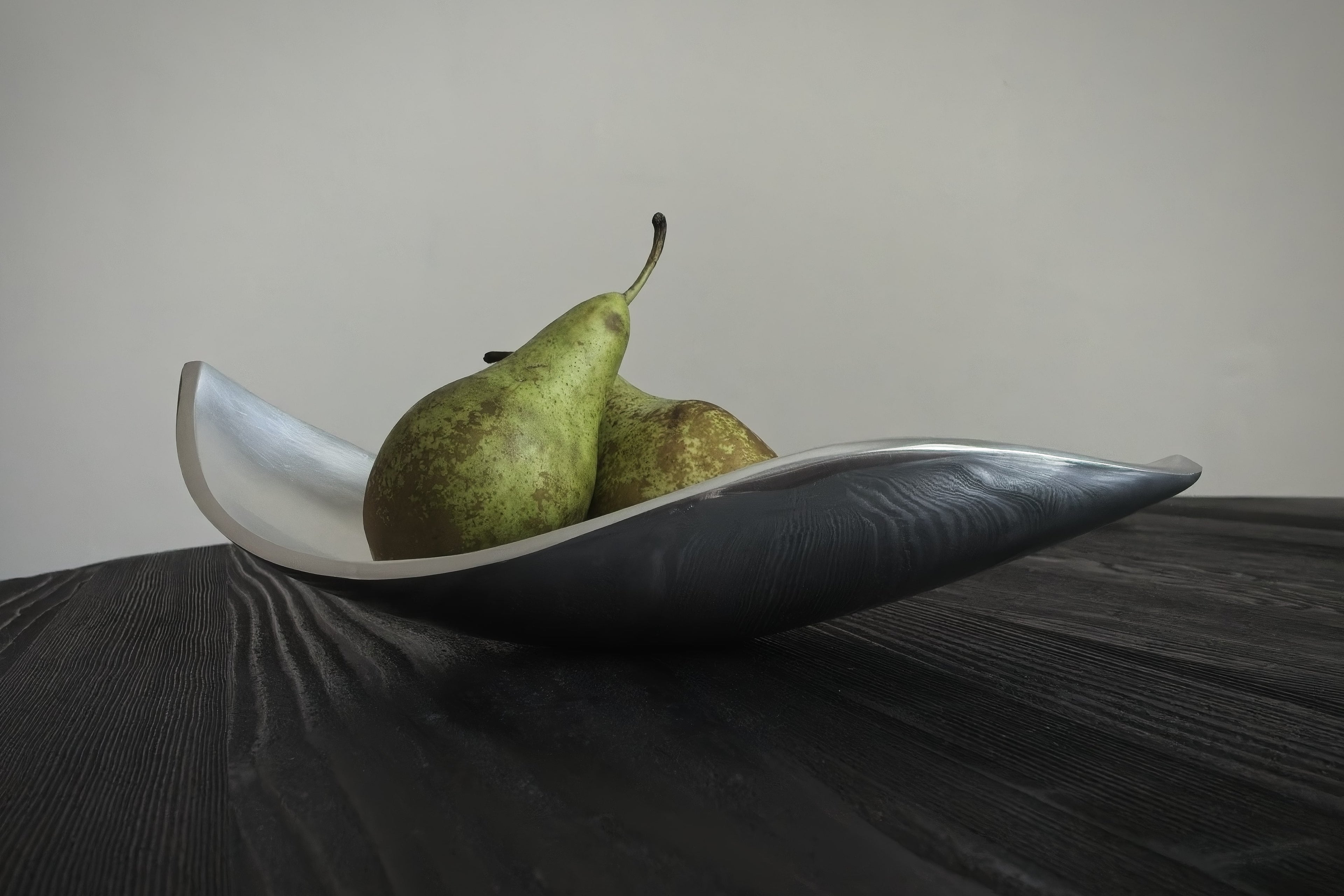 Two pears on a white ceramic dish against a neutral background