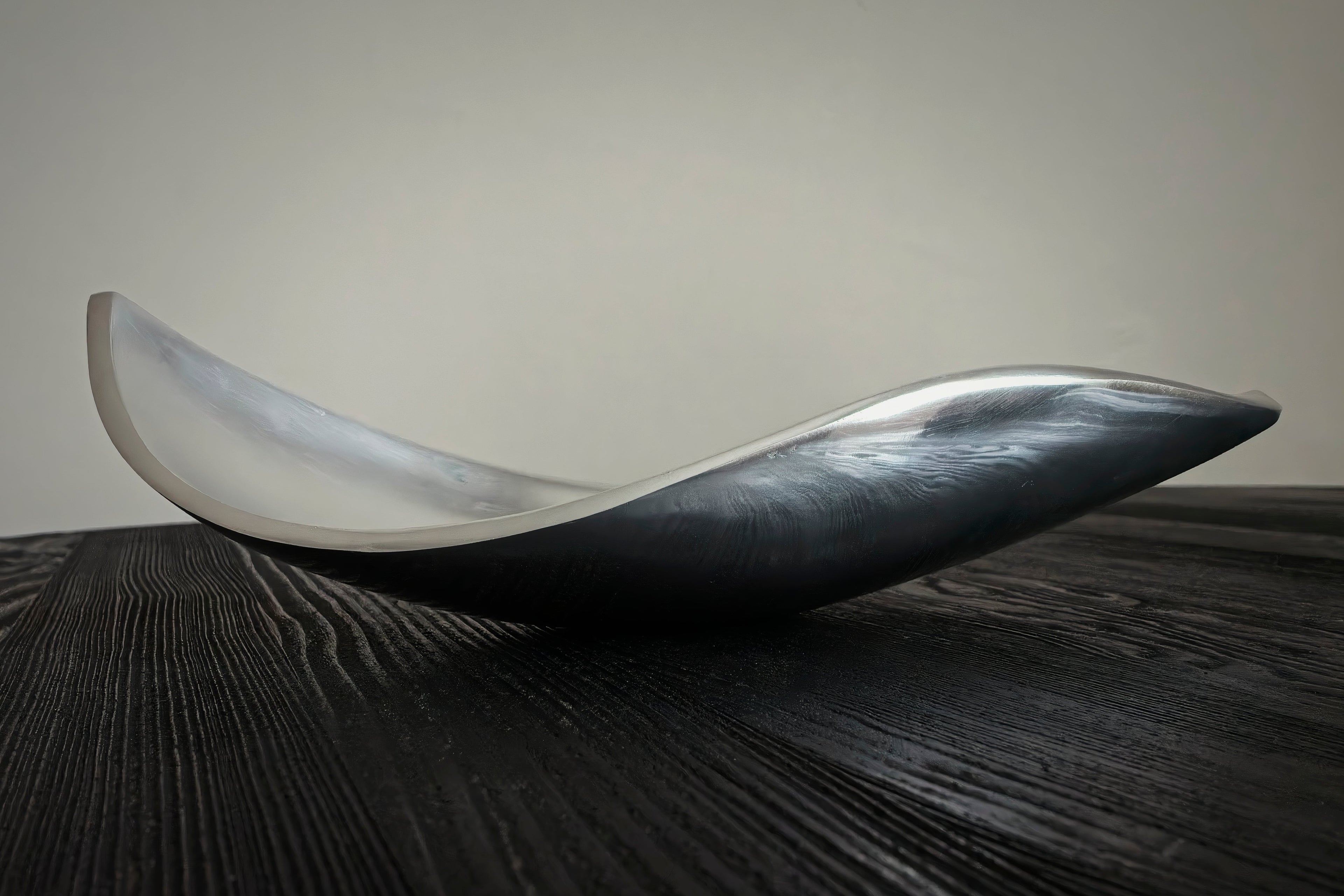 Modern, curved dish on a dark wooden surface with a neutral background