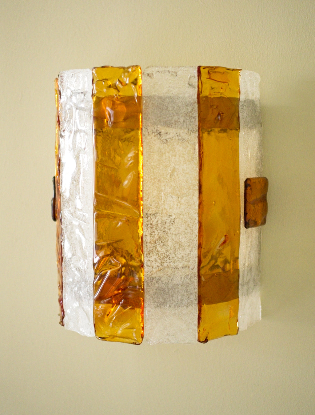 Decorative wall sconce with amber and white stripes on a light green background.