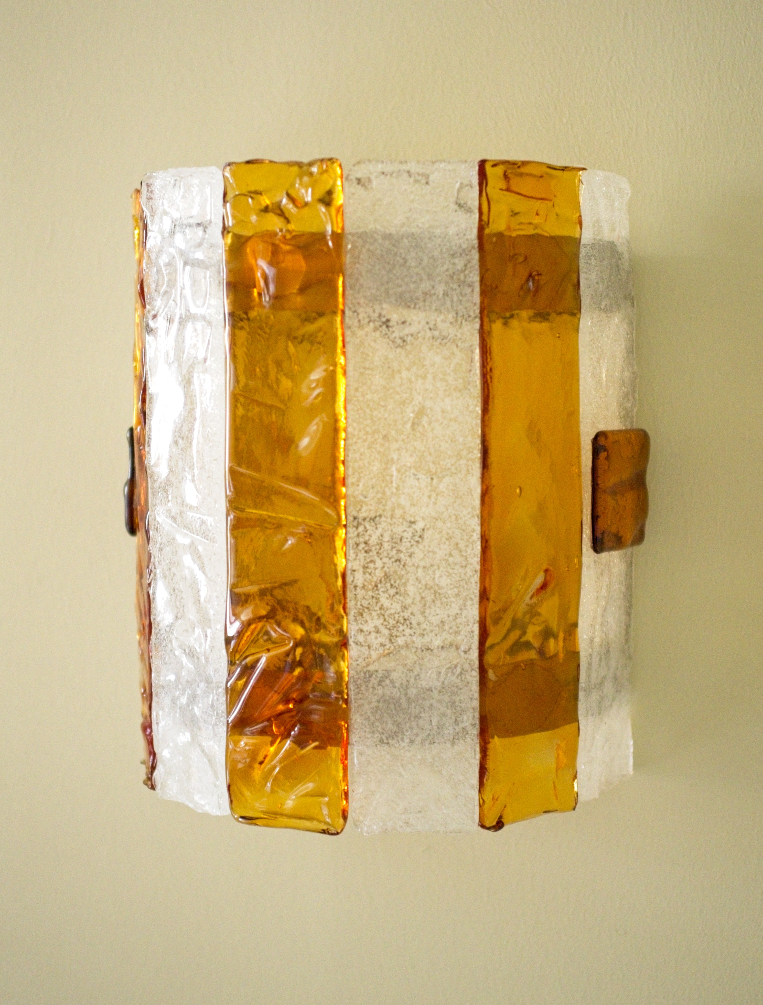 Decorative wall sconce with amber and white stripes on a light green background.