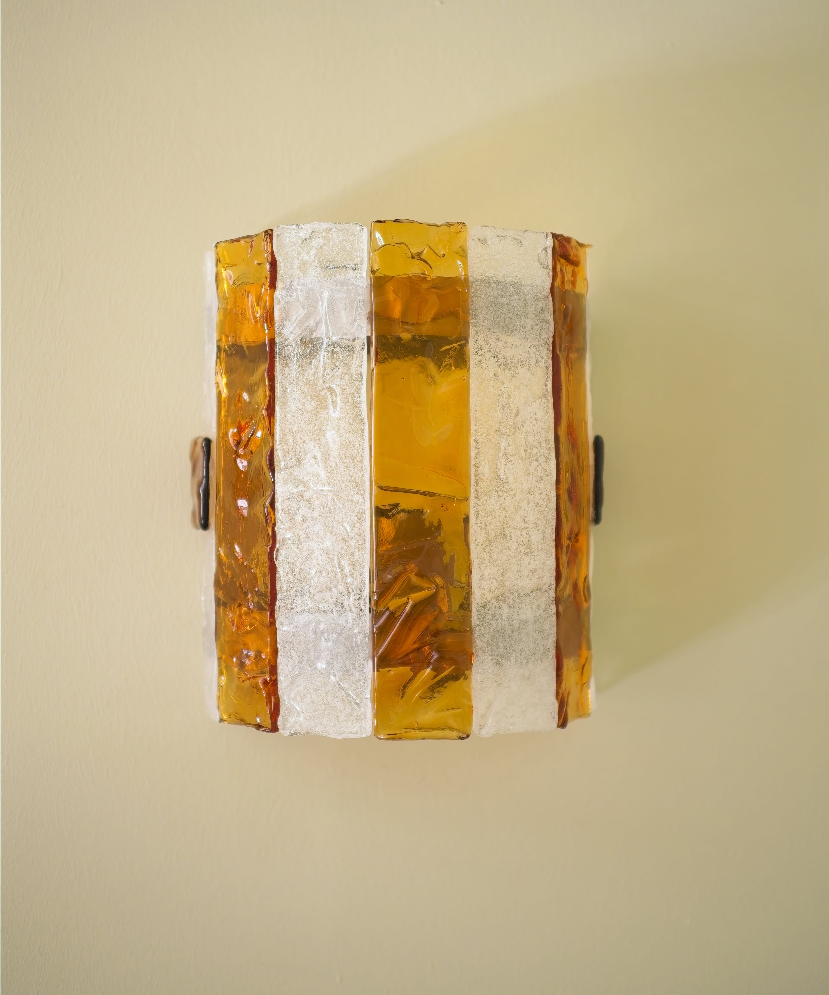 An eclectic vintage mid century modern Carlo Nason for Mazzega wall lamp with amber and clear striped Murano glass panels on a green background.