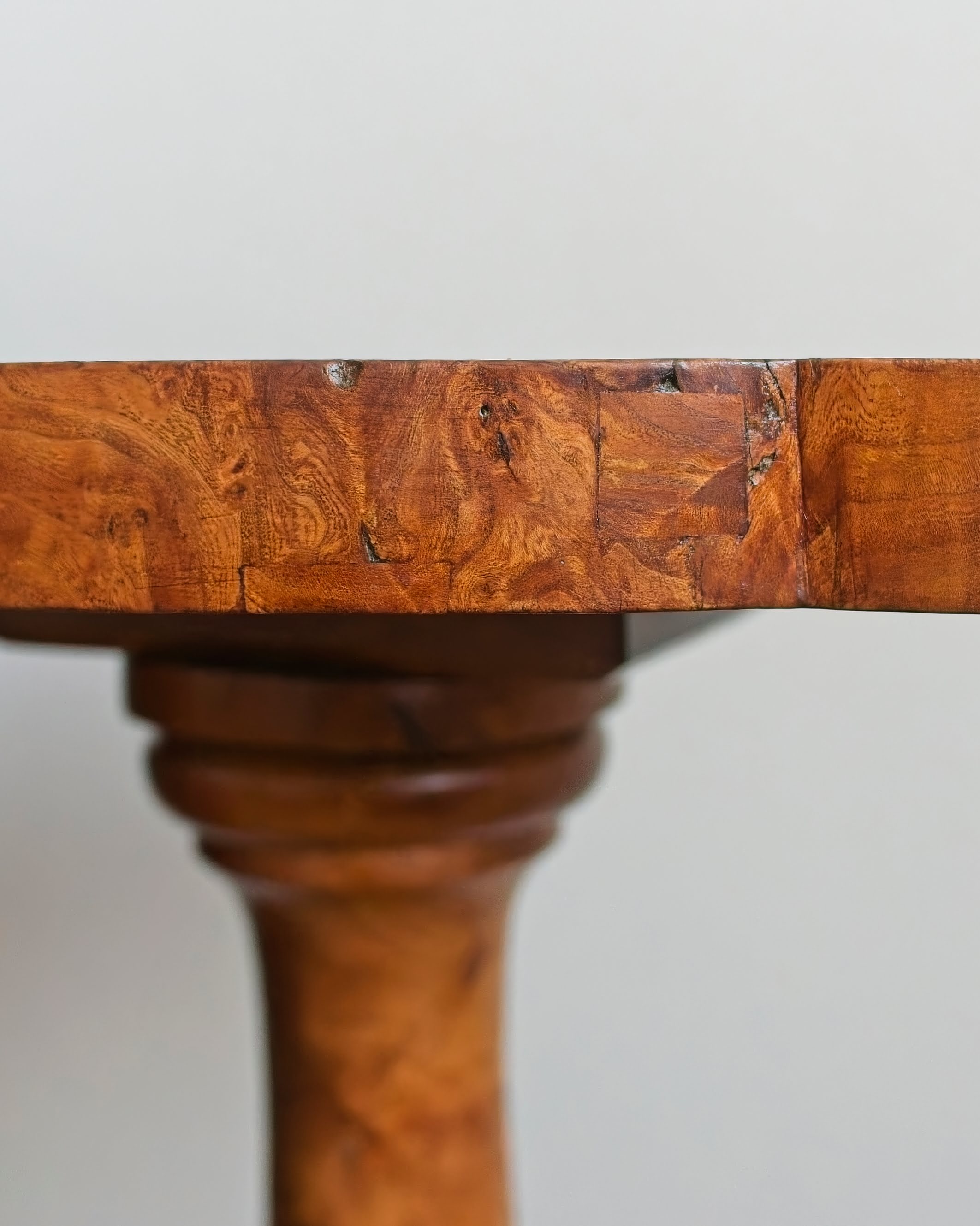A close up of the side of a vintage maple burl wood table top showing an intricate wood grain pattern.