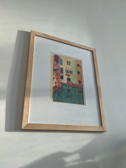 Framed colourful vintage painting of the Venice canals on a white wall.