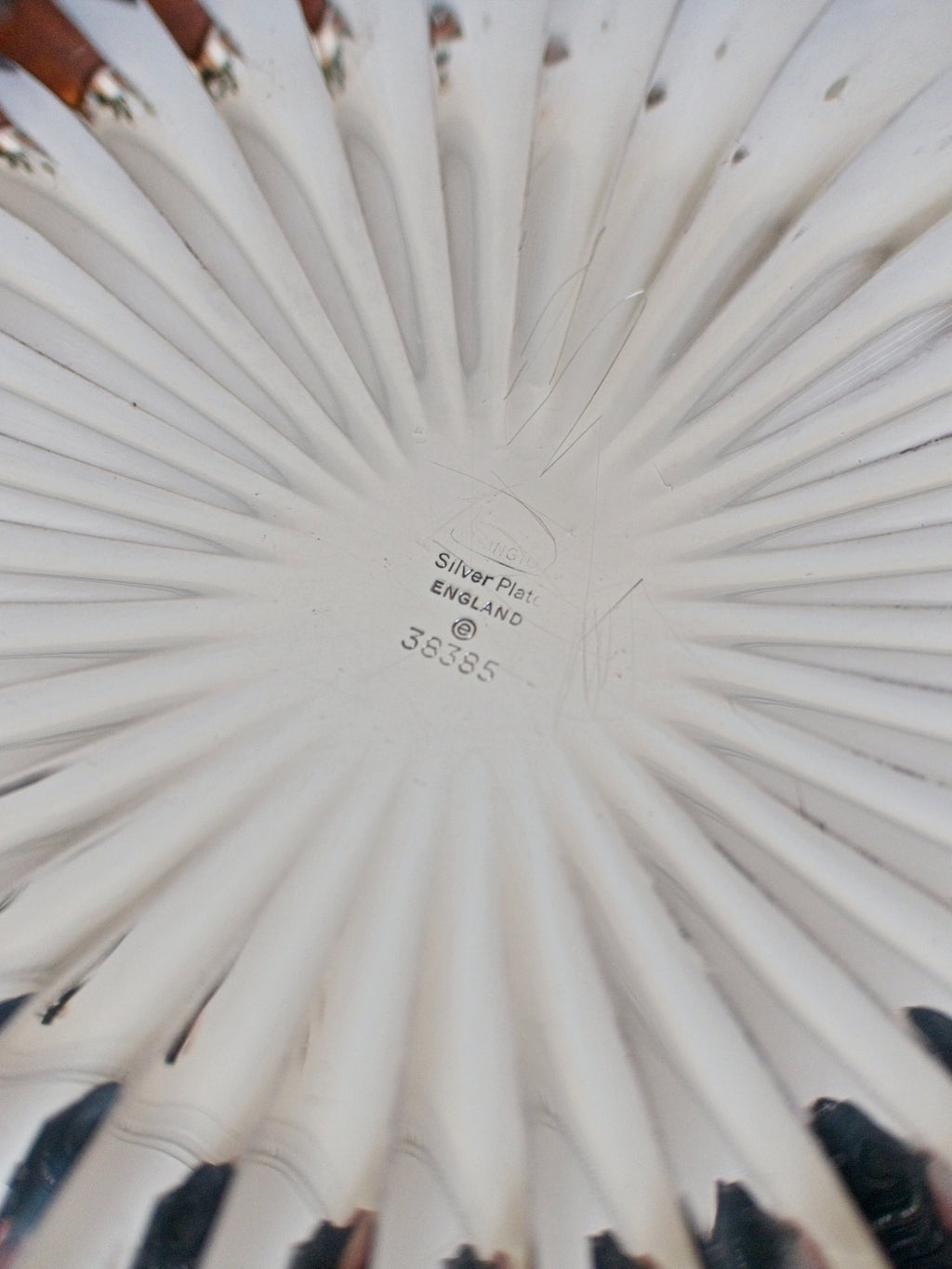 Close-up of a vintage scalloped silver bowl with an Elkington & Co Birmingham engraved makers stamp facing upwards.